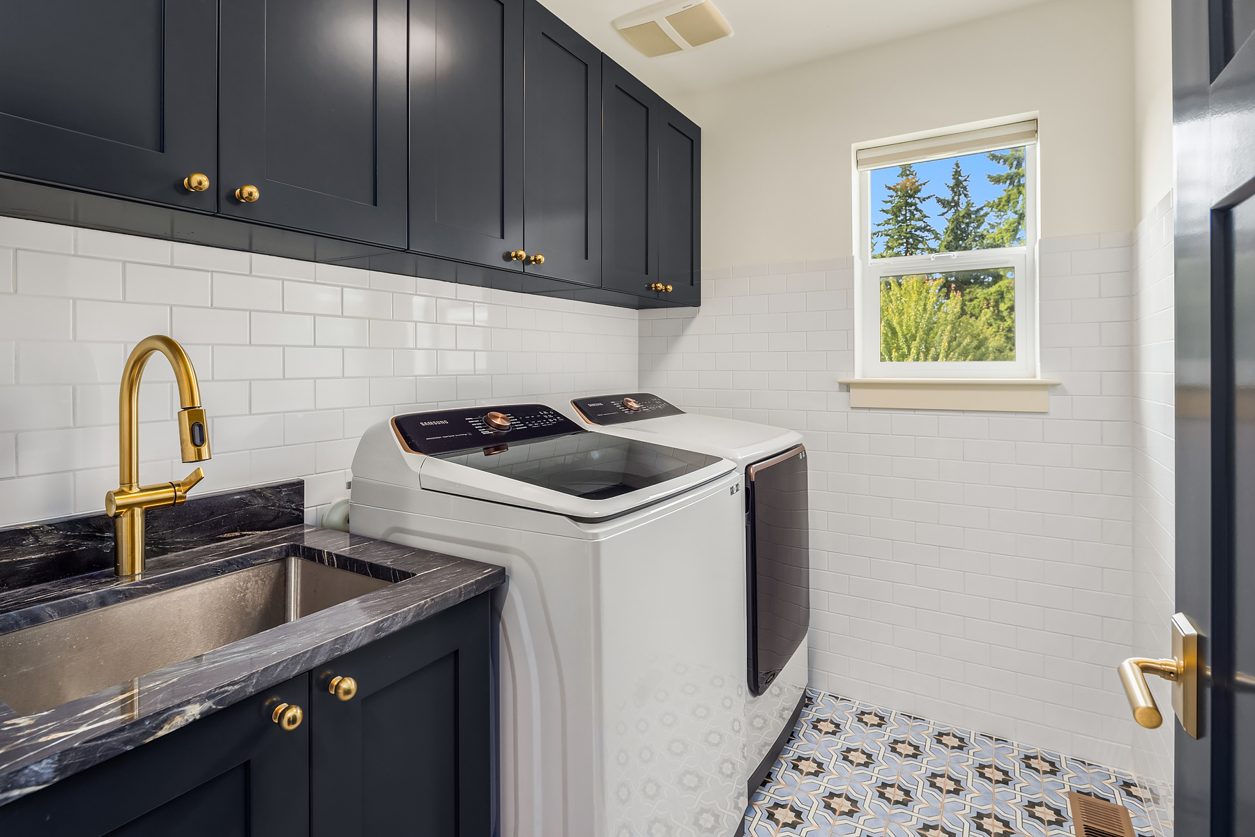 Laundry room with navy cabinetry and patterned tile floor