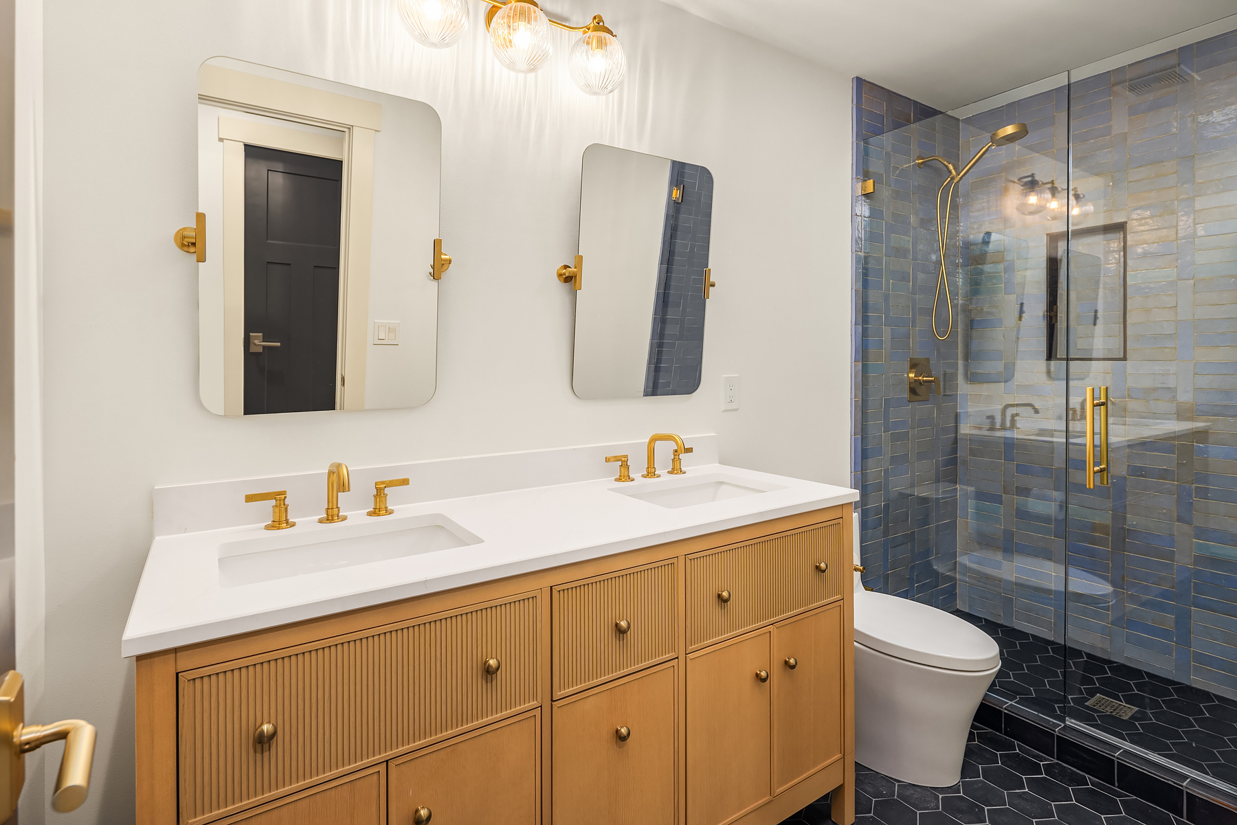 Guest bath with blue tiled shower and brass fittings