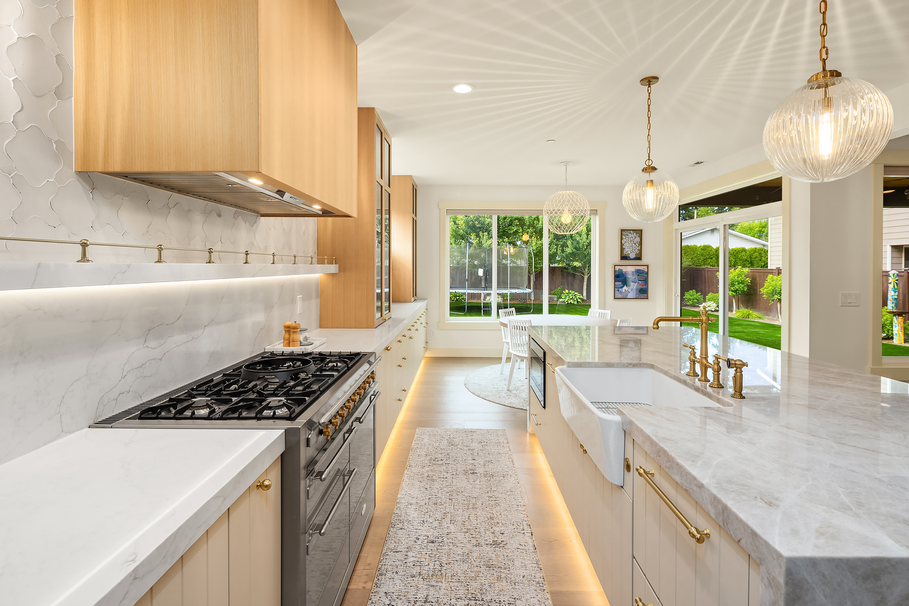 Kitchen range wall with marble backsplash, brass rail and farmhouse sink