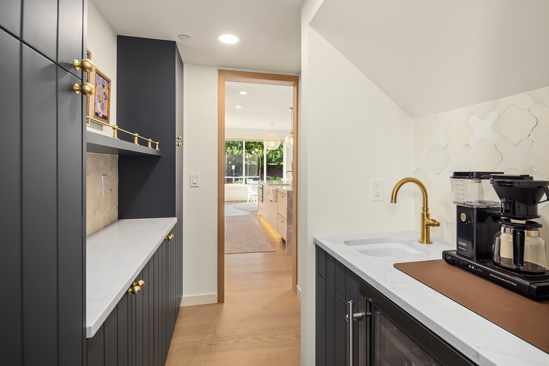 Butler's pantry with charcoal cabinetry and brass fixtures