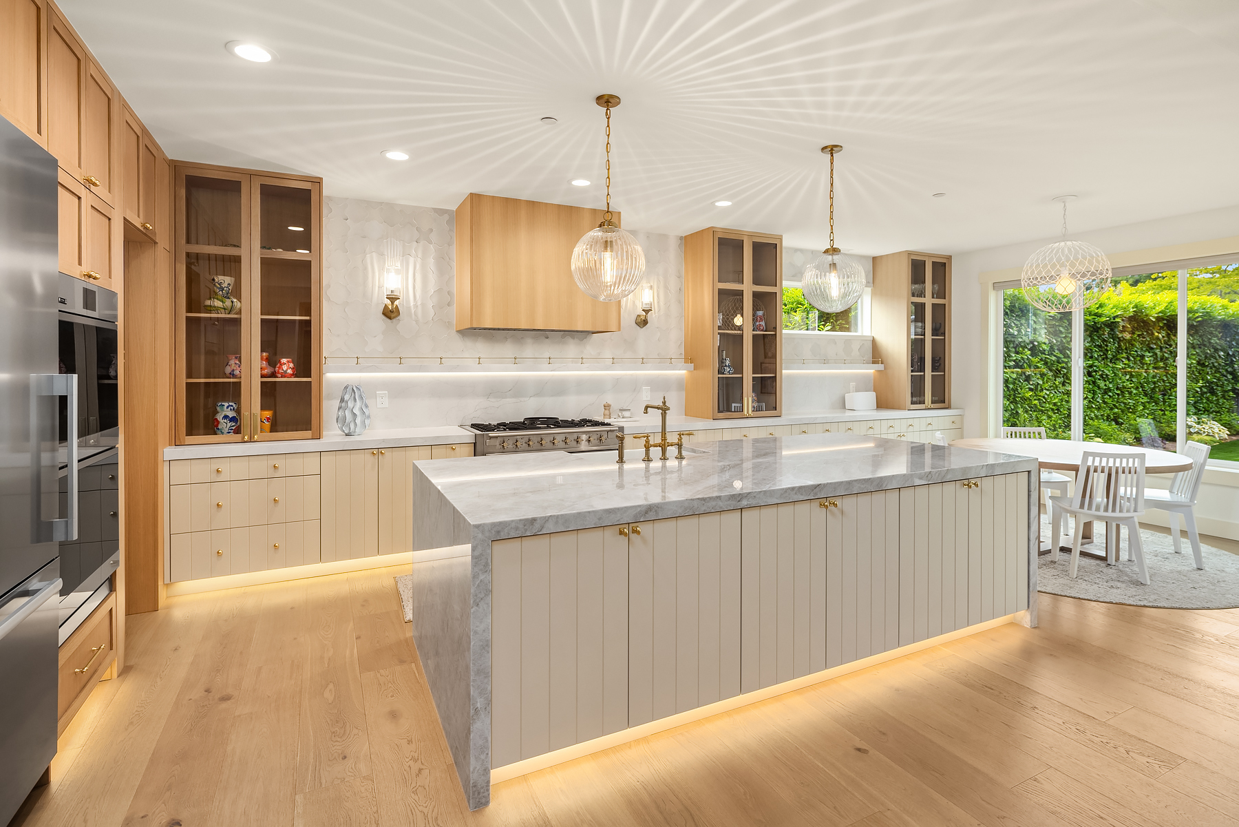 Wide view of the remodeled kitchen with marble island and ribbed glass pendants