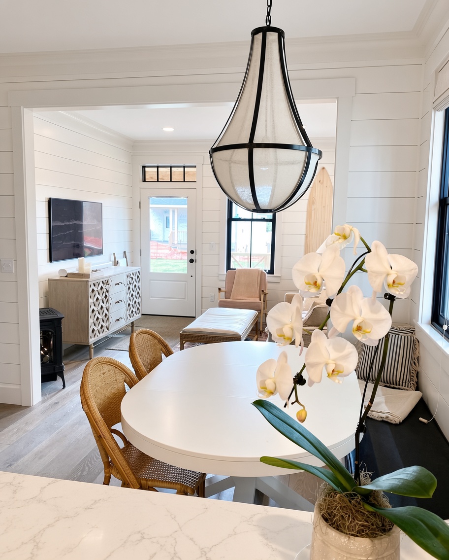 Dining area with white oval table, rattan chairs and lantern pendant