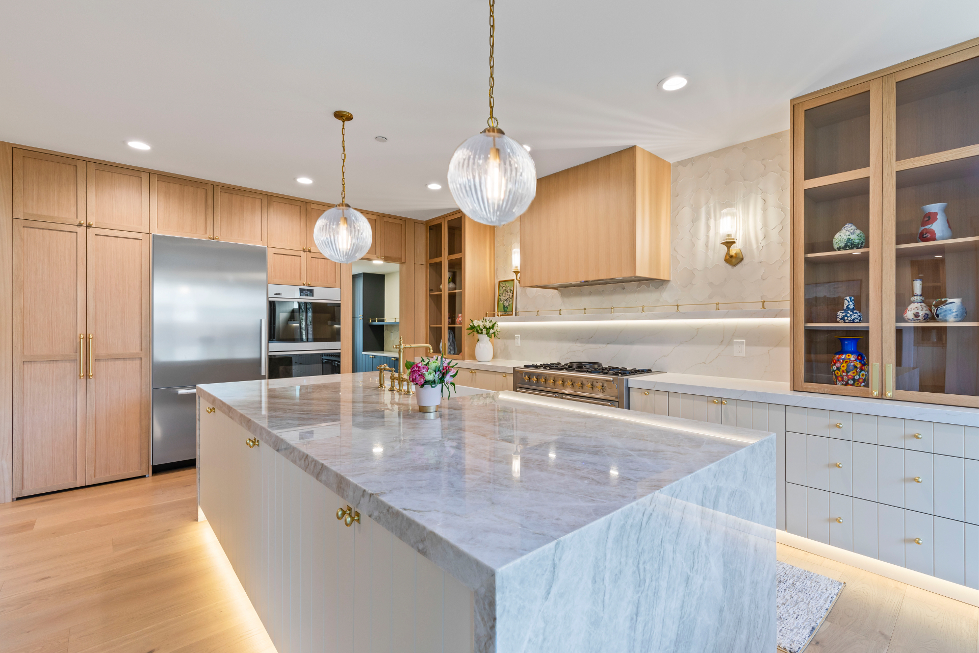 Renovated Edmonds kitchen with quartzite island, cream cabinetry and ribbed glass pendants